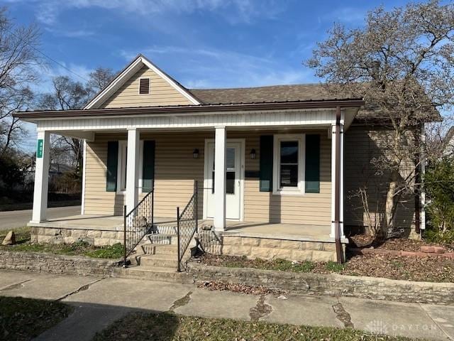 bungalow featuring a porch and roof with shingles