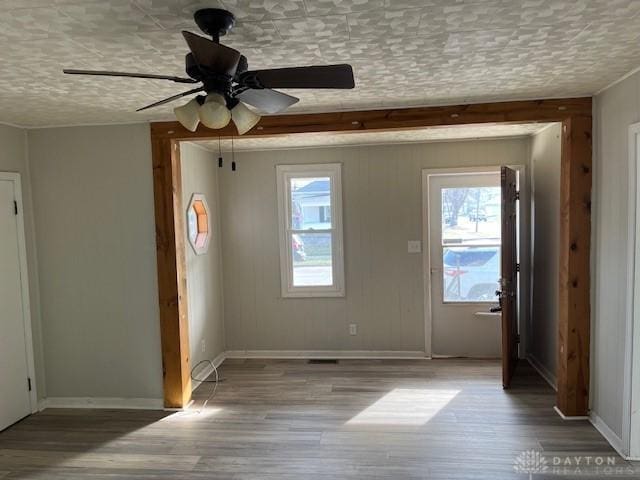 unfurnished room with a textured ceiling, baseboards, ceiling fan, and wood finished floors