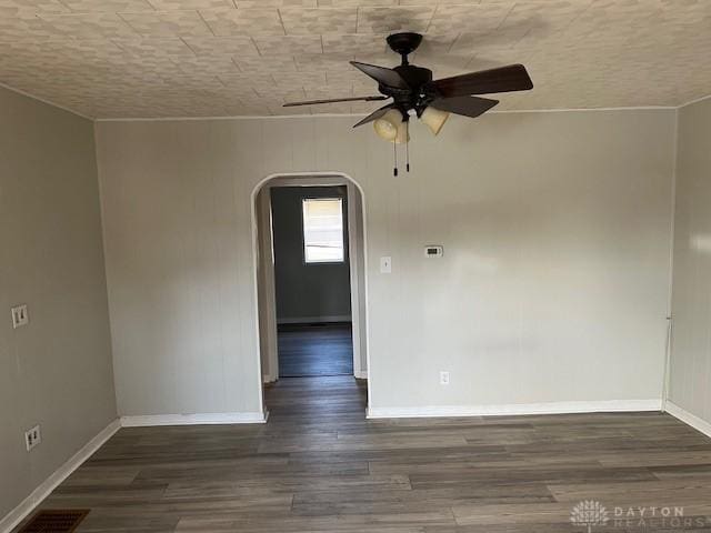 unfurnished room with visible vents, baseboards, ceiling fan, wood finished floors, and arched walkways