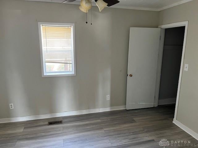 unfurnished bedroom with visible vents, baseboards, wood finished floors, and crown molding