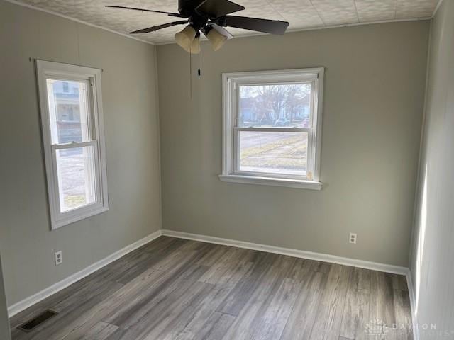 spare room with a wealth of natural light, visible vents, and wood finished floors