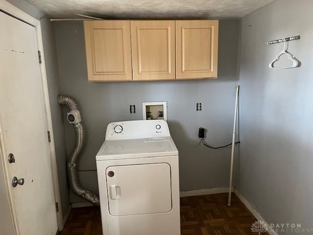 laundry area with baseboards, cabinet space, a textured ceiling, and washer / dryer