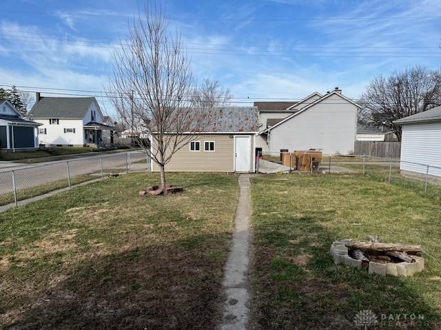 view of yard with an outbuilding, a fire pit, and a fenced backyard