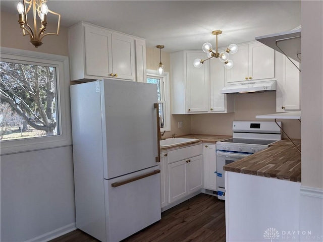 kitchen with under cabinet range hood, white appliances, a notable chandelier, and a sink