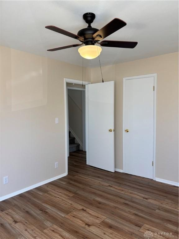 unfurnished bedroom with wood finished floors, baseboards, and ceiling fan