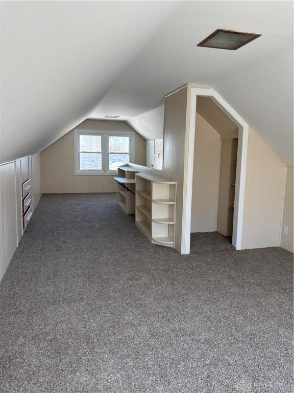 bonus room with vaulted ceiling and carpet floors