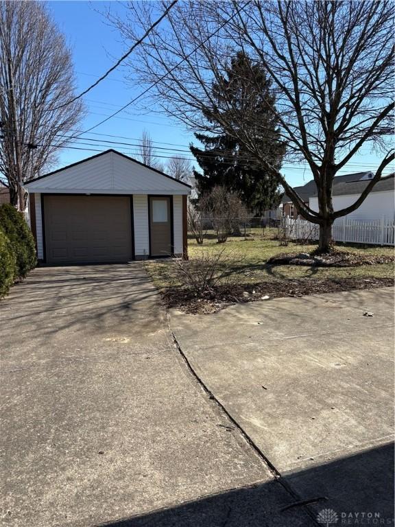 detached garage featuring driveway and fence