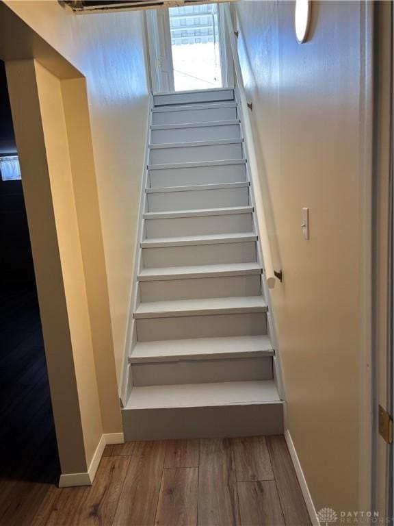 staircase with baseboards and wood finished floors