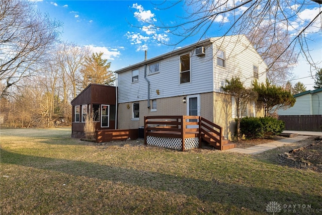 back of property with brick siding, a lawn, and a deck