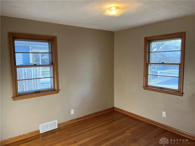 empty room featuring visible vents, baseboards, and dark wood-style flooring