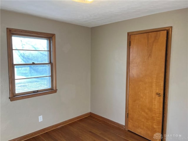 empty room with plenty of natural light, wood finished floors, and baseboards