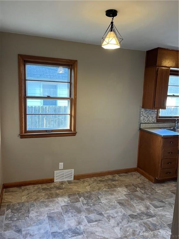 interior space with visible vents, baseboards, backsplash, and stone finish floor