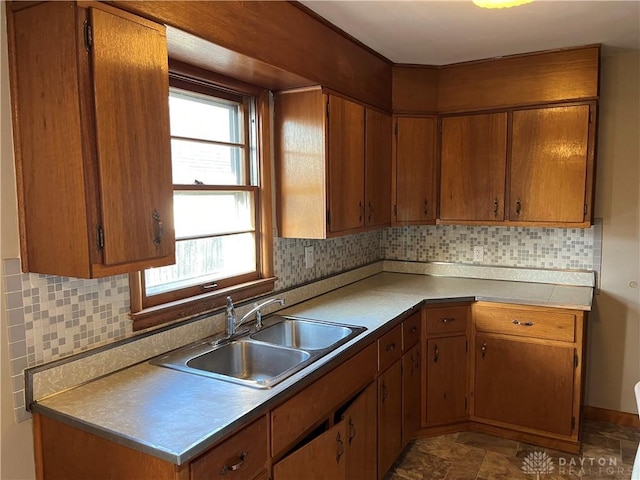 kitchen with a sink, brown cabinets, tasteful backsplash, and light countertops