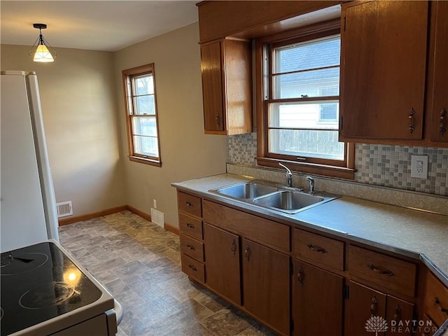 kitchen featuring baseboards, visible vents, electric range, a sink, and decorative backsplash