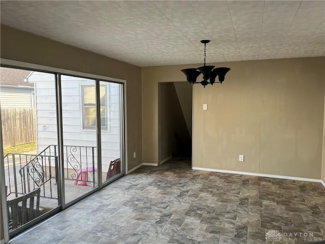 unfurnished dining area featuring baseboards, stone finish flooring, and an inviting chandelier