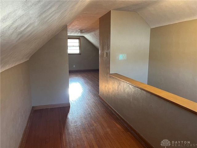 bonus room with baseboards, lofted ceiling, a textured ceiling, and hardwood / wood-style flooring