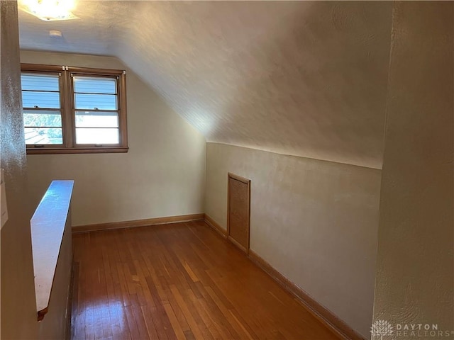 bonus room with hardwood / wood-style flooring, baseboards, lofted ceiling, and a textured ceiling