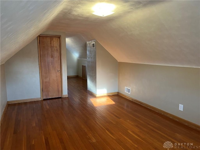 bonus room featuring vaulted ceiling, visible vents, baseboards, and hardwood / wood-style floors