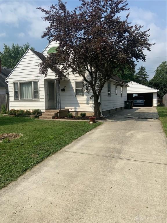 view of front of home featuring a front lawn, an outdoor structure, and driveway