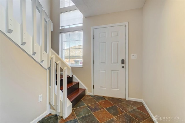 foyer featuring stairway, baseboards, and stone finish flooring