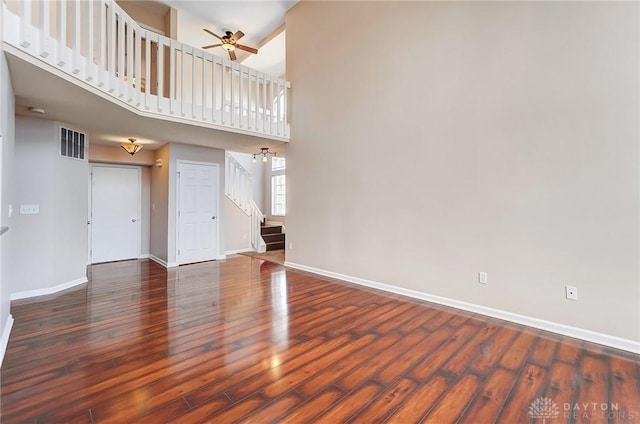 unfurnished living room featuring stairway, a ceiling fan, baseboards, visible vents, and hardwood / wood-style flooring