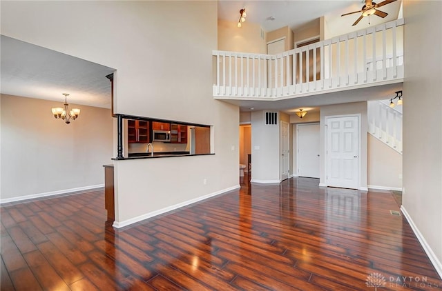 unfurnished living room featuring visible vents, baseboards, wood finished floors, and ceiling fan with notable chandelier