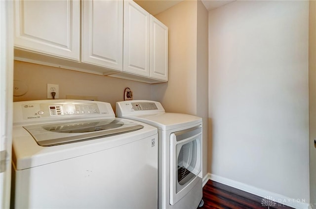 clothes washing area featuring dark wood finished floors, cabinet space, separate washer and dryer, and baseboards