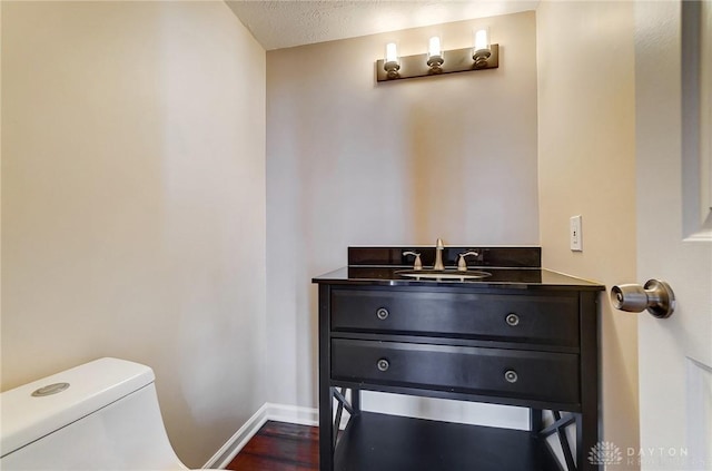 bathroom featuring vanity, wood finished floors, baseboards, a textured ceiling, and toilet