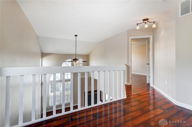 hall featuring visible vents, baseboards, vaulted ceiling, an upstairs landing, and wood finished floors