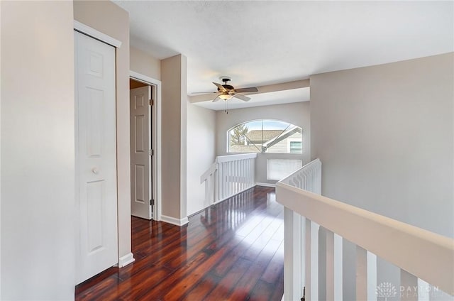 hallway with dark wood-style floors, an upstairs landing, and baseboards