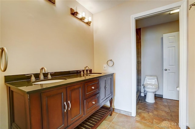 bathroom featuring a sink, baseboards, toilet, and double vanity