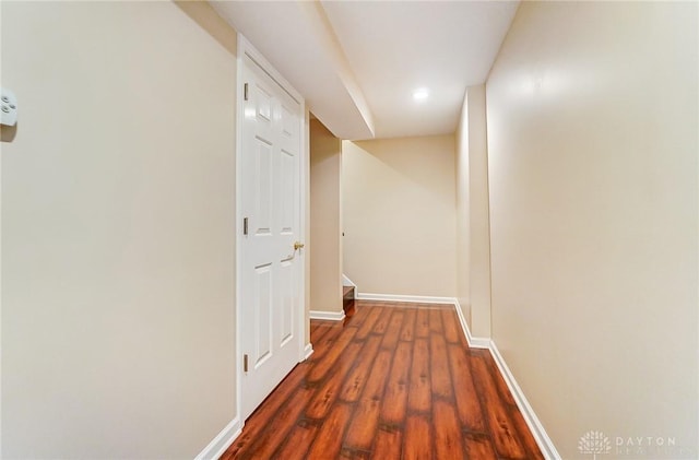 corridor with dark wood-type flooring and baseboards