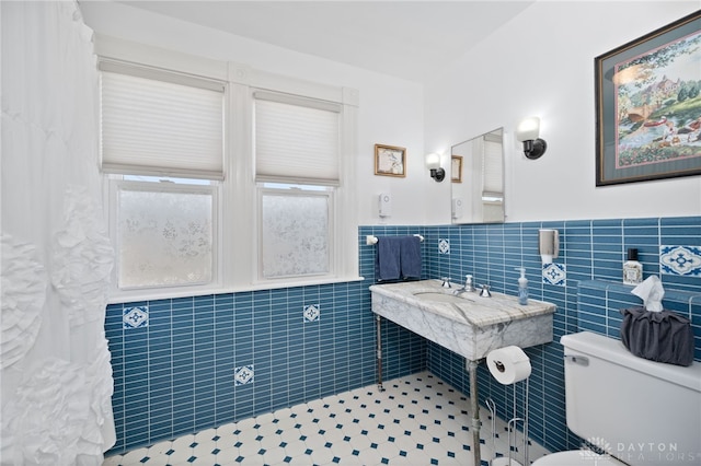 bathroom featuring tile walls, toilet, and a wainscoted wall