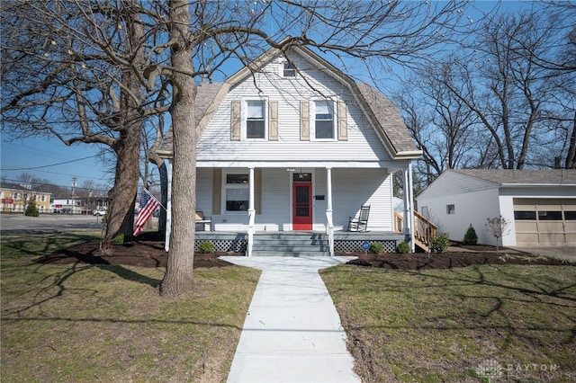 colonial inspired home with a porch, a gambrel roof, a front yard, and a garage