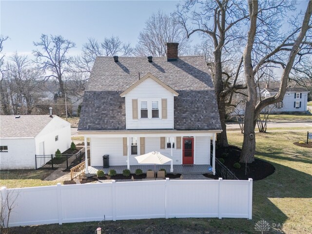 view of front of home featuring a porch, a shingled roof, a chimney, and a fenced front yard