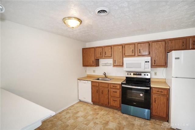 kitchen featuring visible vents, light countertops, brown cabinets, white appliances, and a sink