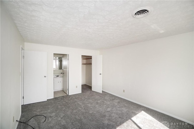 unfurnished bedroom featuring visible vents, a sink, a closet, carpet flooring, and baseboards