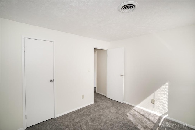 unfurnished bedroom featuring visible vents, baseboards, a textured ceiling, and carpet flooring