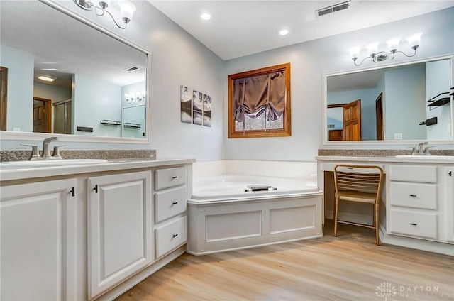 bathroom featuring a sink, visible vents, a garden tub, and wood finished floors