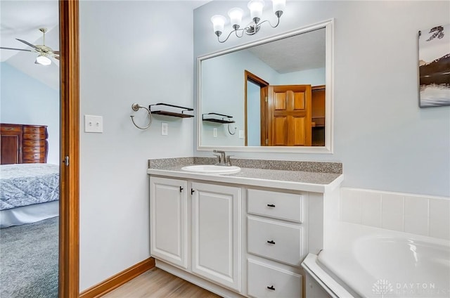 ensuite bathroom featuring connected bathroom, baseboards, a bath, vanity, and a ceiling fan