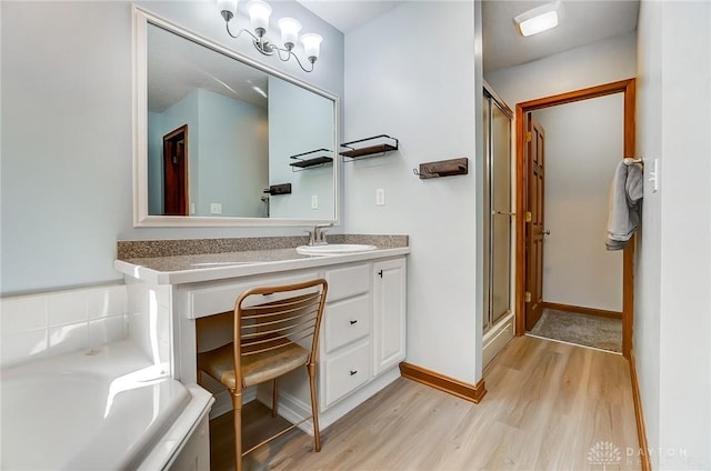 bathroom featuring wood finished floors, a shower stall, baseboards, a bath, and vanity