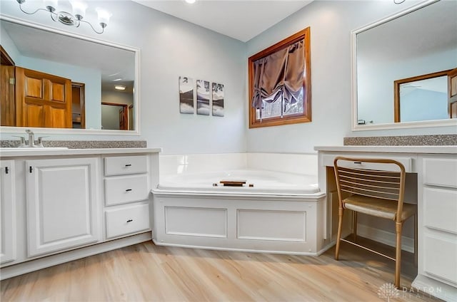 full bathroom featuring vanity, a bath, and wood finished floors