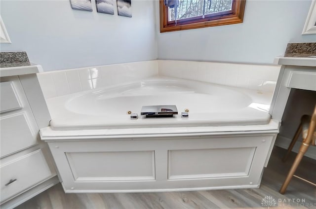 full bath featuring vanity, wood finished floors, and a whirlpool tub