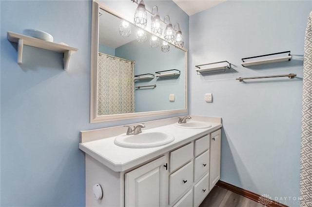 bathroom featuring a sink, baseboards, wood finished floors, and double vanity