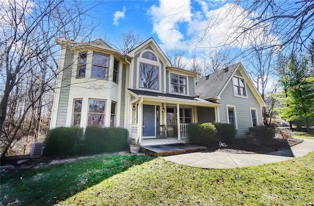 view of front of home featuring central AC unit, covered porch, and a front lawn