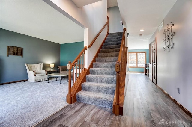 stairway featuring wood finished floors, visible vents, and baseboards