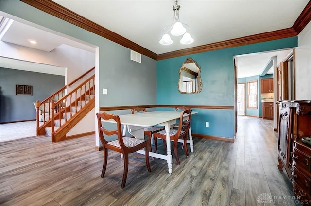 dining room with stairway, wood finished floors, visible vents, baseboards, and crown molding