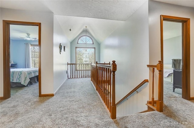 hallway with an upstairs landing, carpet flooring, plenty of natural light, and lofted ceiling