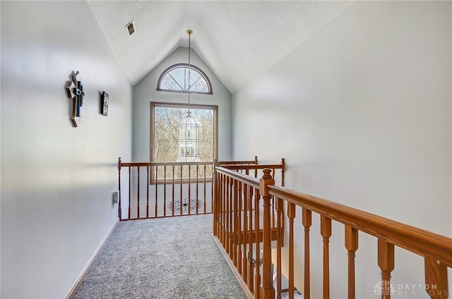 hallway with baseboards, carpet floors, visible vents, vaulted ceiling, and an upstairs landing