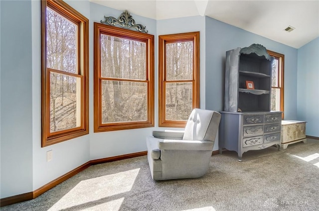 living area featuring visible vents, carpet flooring, lofted ceiling, and baseboards